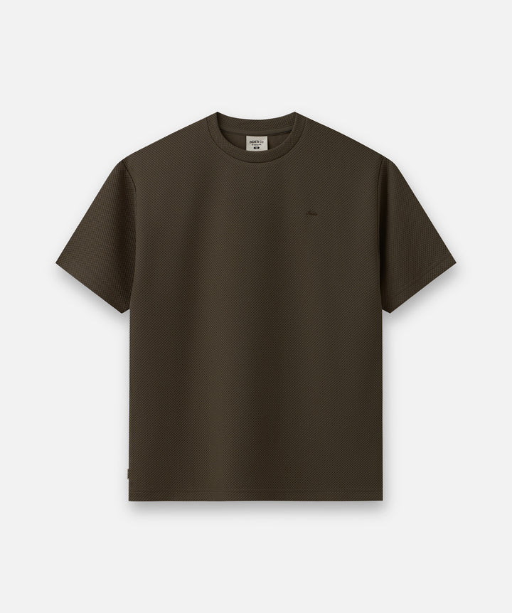 A dark brown short-sleeve crewneck t-shirt with a small tonal embroidered logo on the left chest, displayed flat against a light gray background.